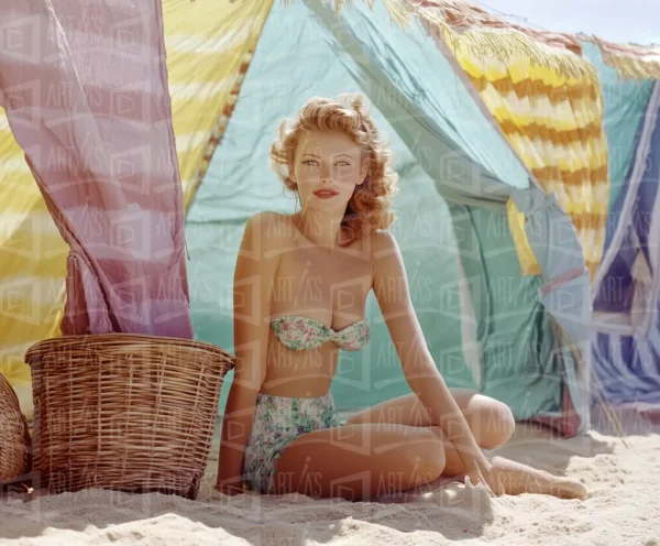 Retrato de mujer sentada en la playa, con fondo de toldos de colores. | CUADROS DE ATREZZO PARA CINE Y PUBLICIDAD